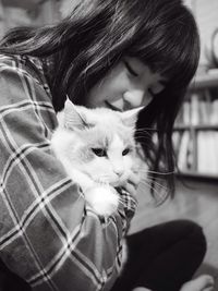 Close-up of teenage girl with cat sitting at home