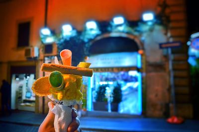 Cropped image of person holding ice cream cone at night