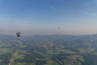 Hot air balloons flying over landscape against sky