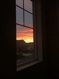 Silhouette buildings seen through window during sunset