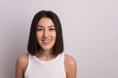 Portrait of smiling young woman against white background