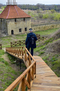 Rear view of man walking on boardwalk