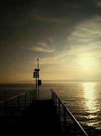 Silhouette pier over sea against sky during sunset