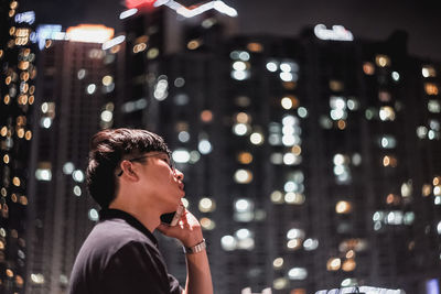 Portrait of young man looking at illuminated city