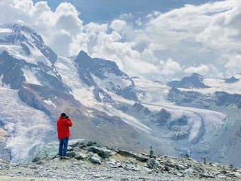 Rear view of person photographing snowcapped mountain against sky