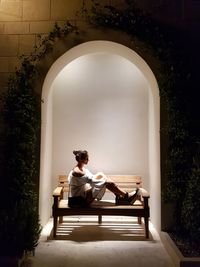 Young woman sitting on seat against built structure