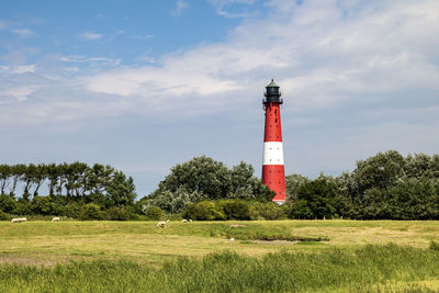 Lighthouse on field against sky