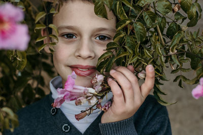 Portrait of smiling boy holding plant outdoors