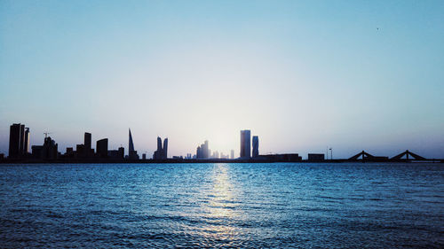 Sea by modern buildings against clear sky