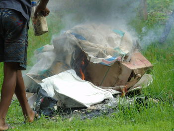 Low section of man standing by burning garbage on land