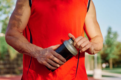 Midsection of woman holding red while standing outdoors