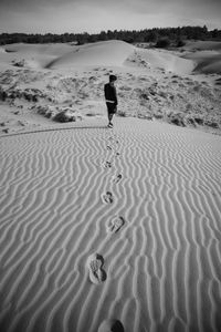 Rear view of man standing on sand at desert