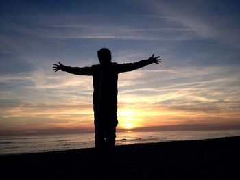 Silhouette man on beach against sky during sunset