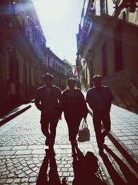 Full length of family walking on street amidst buildings in city during sunny day