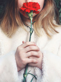 Midsection of girl holding red flower