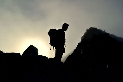Silhouette man hiking on mountains against sky