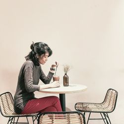 Side view of young woman sitting on table