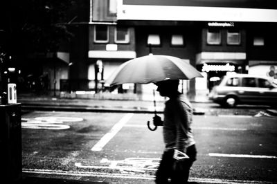 Side view of man walking on street with umbrella