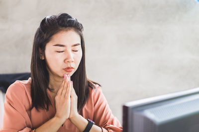 Portrait of young woman sitting against wall