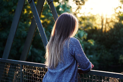 Rear view of woman standing against railing