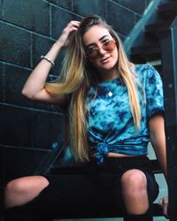 Portrait of young woman sitting against wall