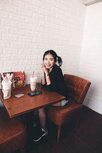 Portrait of young woman sitting on table at home