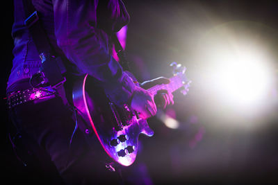 Midsection of man playing guitar at music concert