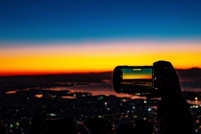 Person photographing landscape during sunset