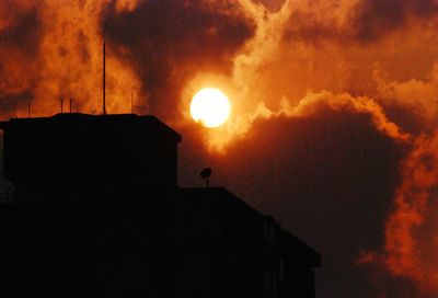 Silhouette of building against cloudy sky at sunset