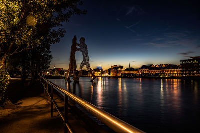 Illuminated bridge over river against sky at night