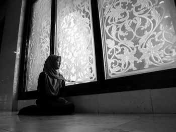 Side view of woman sitting on floor at home