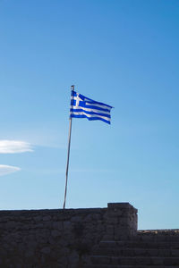 Low angle view of flag against blue sky
