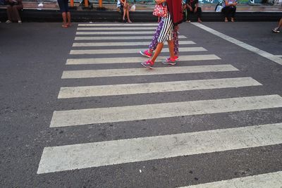 Low section of people walking on zebra crossing