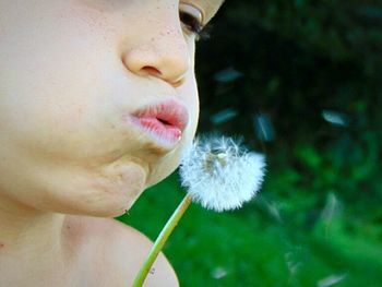 Close-up portrait of woman with dandelion flower