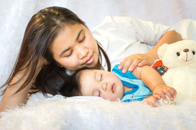 Mother lying by sleeping son on fur sheet at home