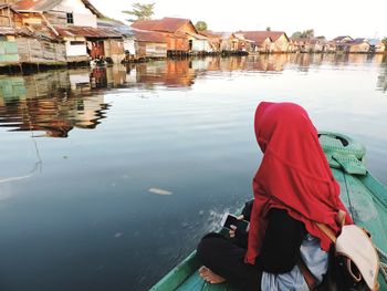 Rear view of men sitting on boat in lake