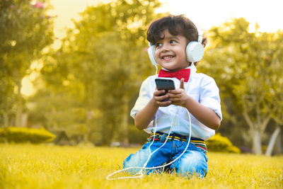 Portrait of cute boy holding mobile phone in field