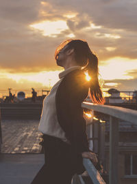 Side view of man standing against sky during sunset