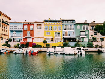 Boats moored by river against buildings in city