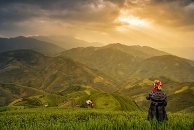 Rear view of woman standing in field against sky