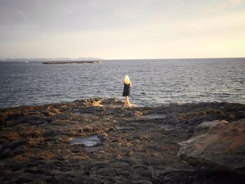 Man standing on rocks at seaside