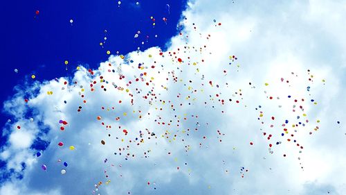 Low angle view of balloons flying against blue sky