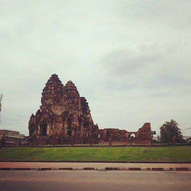 architecture, sky, built structure, building exterior, cloud - sky, grass, history, cloud, road, cloudy, travel destinations, tree, famous place, day, outdoors, landscape, travel, the past, ancient, incidental people