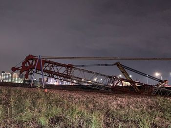 Low angle view of cranes on field against sky