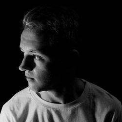 Close-up of thoughtful man against black background