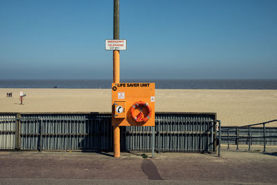 Information sign on beach against clear sky