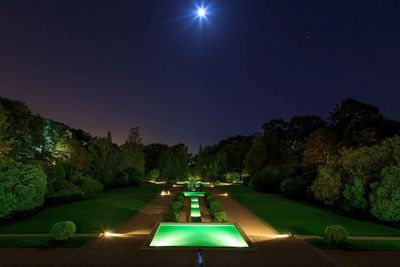 Illuminated road against sky at night