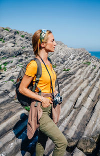 Side view of young woman standing against mountain