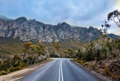 Road by mountains against sky