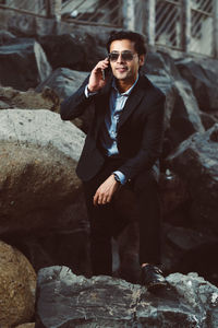 Young businessman talking on mobile phone while standing amidst rocks